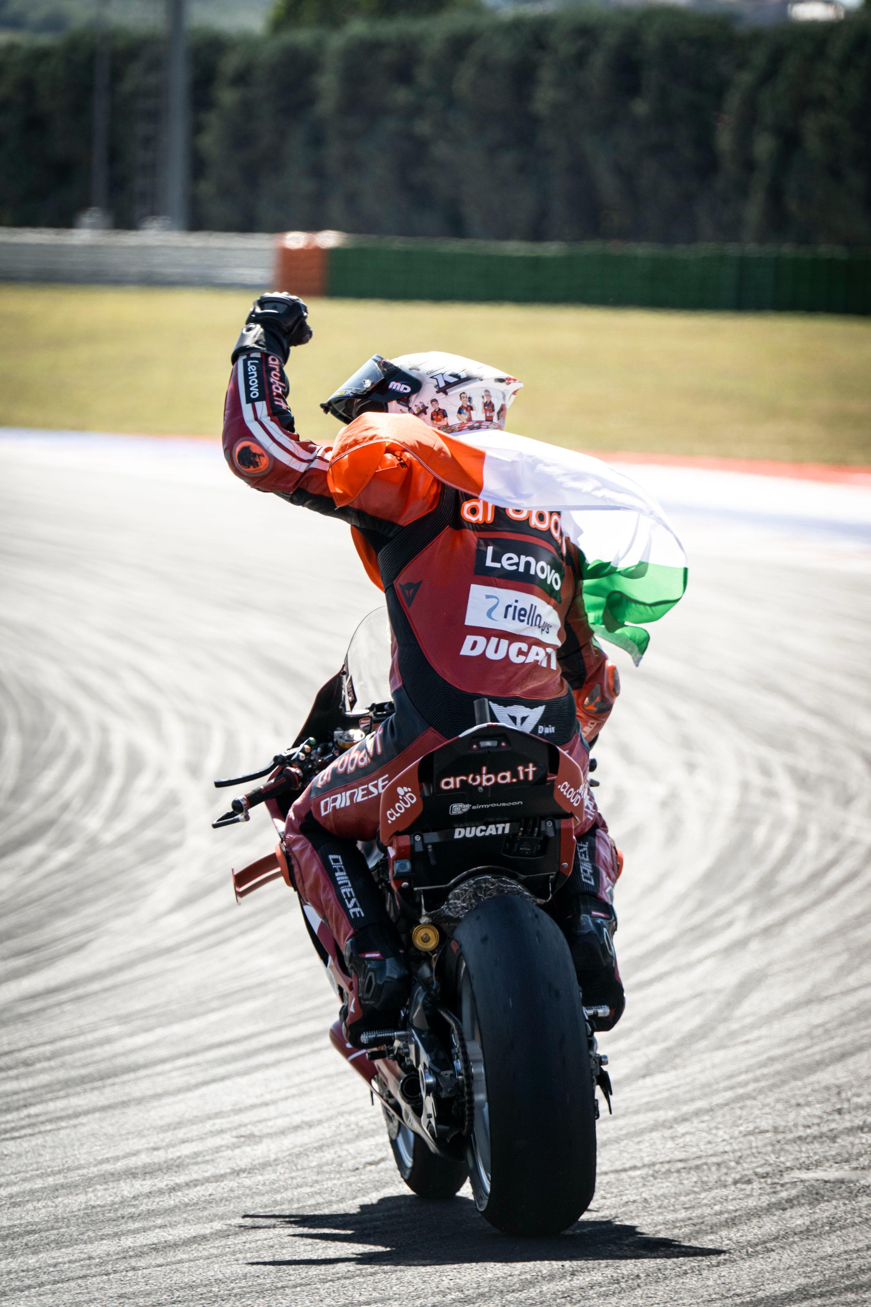 Nicolò Bulega festeggia con la bandiera italiana in wheelie sulla Ducati Panigale V4R al Misano World Circuit 2026