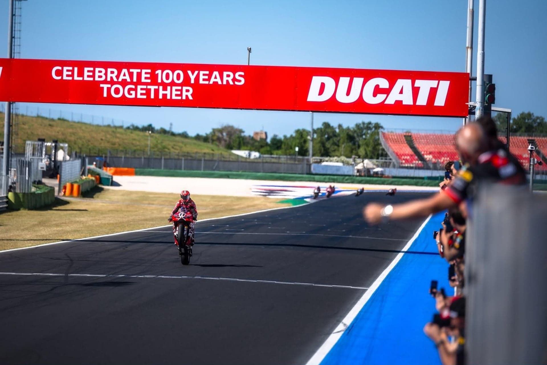 Nicolò Bulega in wheelie sotto lo striscione Celebrate 100 Years Together al centenario Ducati